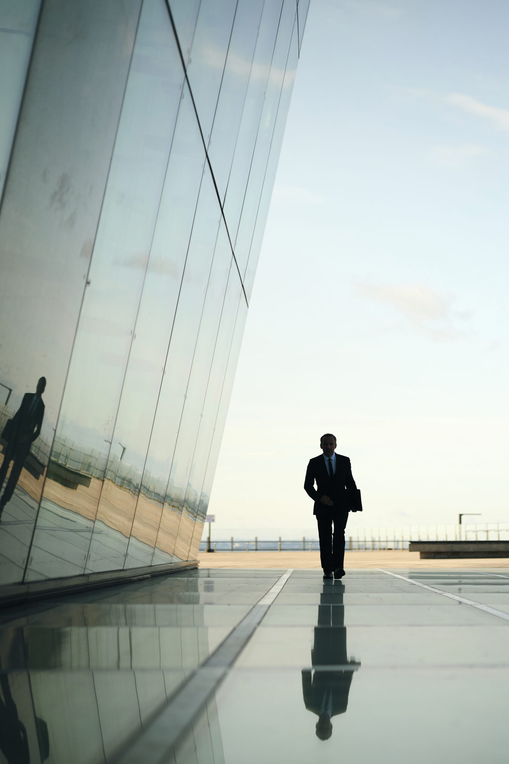 Business executive walking beside a modern glass office building, symbolizing leadership, corporate accountability, and rebuilding trust after a crisis.
