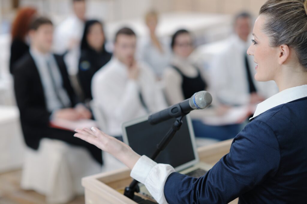 Female executive speaking at a corporate event about leadership communication and business trust