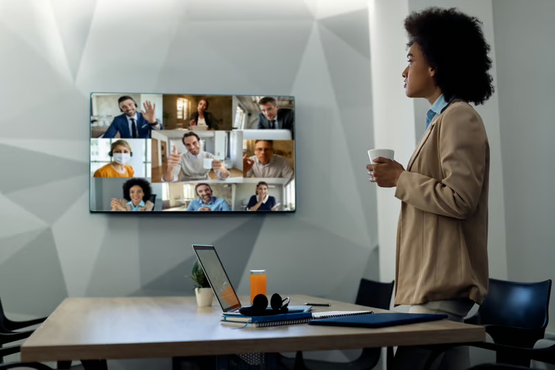 Leader facilitating a hybrid team meeting with remote employees on a video conference, demonstrating effective workplace communication and collaboration.